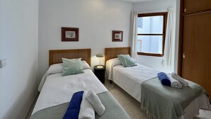 Hotellihuone, jossa on kaksi sänkyä, ikkuna ja ovi.