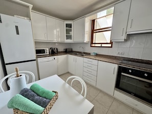 A compact kitchen with white cabinets, a microwave, a toaster, and a sink. - Sea front partment on Puerto Pollença Pinewalk, Kika (Pollensa / Pollença)