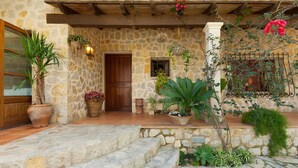 Un bâtiment en pierre avec une porte en bois, des plantes en pot et un toit recouvert de tuiles.