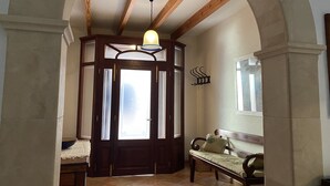 A hallway with a wooden door, a bench, and a hanging light fixture.