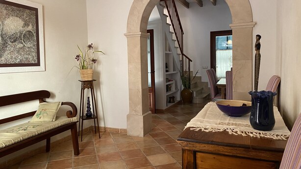 A spacious hallway with a wooden bench, a table with a vase, and a staircase leading to another room.