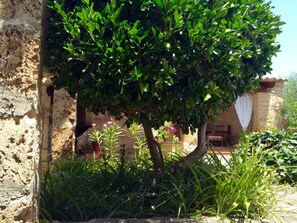 A rustic stone building with a lush green tree in front. - Charming stone clad family villa with pool La Font (Pollensa / Pollença)