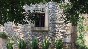 A stone wall with a window and potted plants. - Charming stone clad family villa with pool La Font (Pollensa / Pollença)