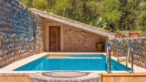 A stone-walled swimming pool with a wooden door and a stone fountain. - Charming stone clad family villa with pool La Font (Pollensa / Pollença)