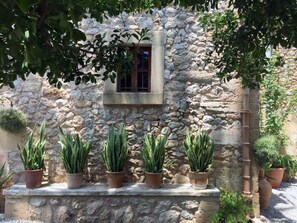 Un mur de pierre avec une fenêtre et des plantes en pot.