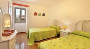 A bedroom with two beds, a window, a mirror, and a wall with toy cars.