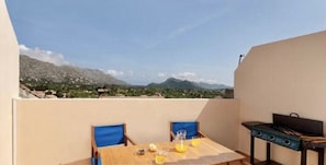 Un espace repas comprenant une table et des chaises, un barbecue et une vue sur les montagnes.