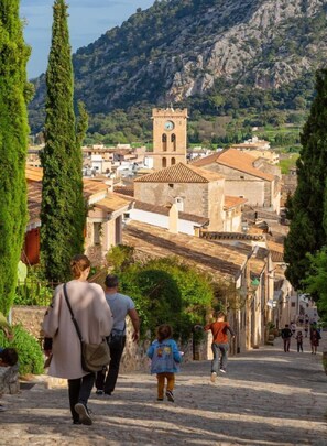 A cobblestone street leading to a historic town with a prominent clock tower. - Fabulous situation, townhouse in Pollensa, Gruat. (Pollensa / Pollença)
