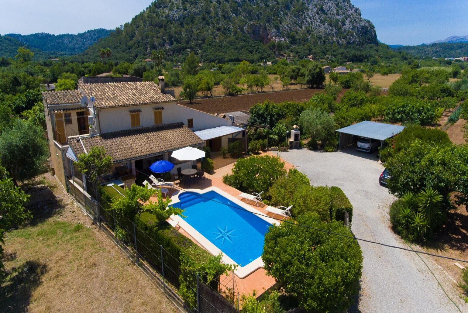 A villa with a swimming pool, outdoor seating, and a view of the surrounding landscape.