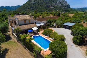 A villa with a swimming pool, outdoor seating, and a view of the surrounding landscape.