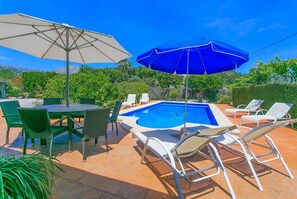 A poolside area with a table and chairs, two umbrellas, and lounge chairs. - Nice villa with pool close to Pollença. Can Tomeu. (Pollensa / Pollença)