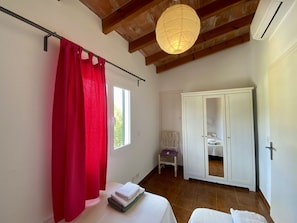 A bedroom with a bed, a wardrobe, a window with curtains, a chair, and a hanging light fixture. - Walking distance to town, two bedroom villa Jero. (Pollensa / Pollença)