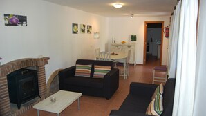 Un salon avec une cheminée, deux canapés, une table basse et, au fond, un coin repas.