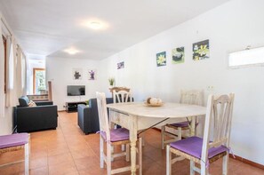 A dining area with a round table and chairs, a television, and artwork on the walls. - Walking distance to town, two bedroom villa Jero. (Pollensa / Pollença)