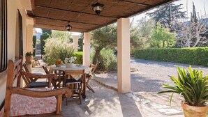 Une terrasse extérieure avec une table et des chaises, entourée de plantes en pot et offrant une vue sur le jardin.