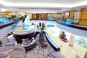 A multi-level hotel lobby with a glass railing, seating areas, and a reception desk. - Xiamen Jingmin Central Hotel (Xiamen)