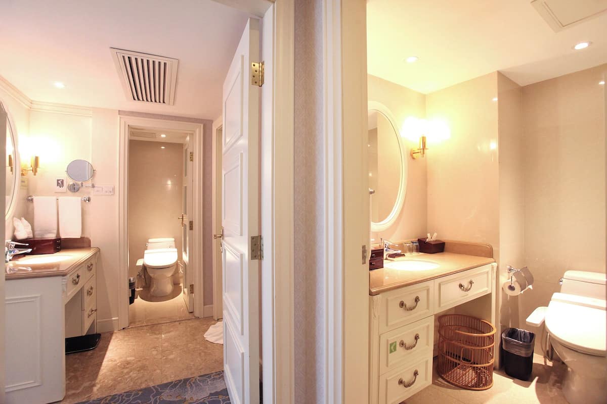Une salle de bain d’hôtel équipée de toilettes, d’un lavabo, d’un miroir et d’un porte-serviettes.