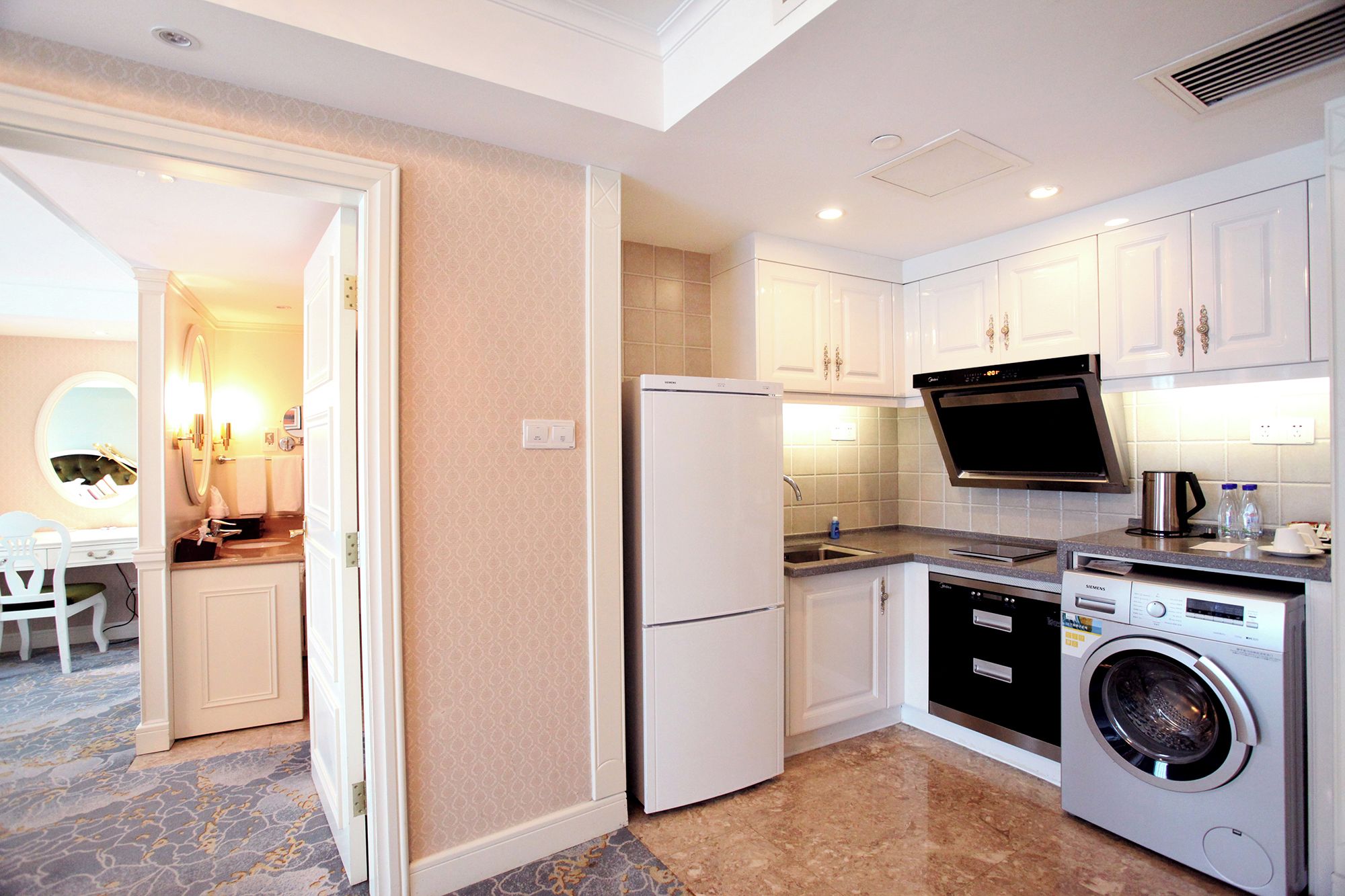 A compact kitchen with white cabinets, a built-in oven, a microwave, and a washing machine.