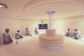A room with a central cylindrical structure, a flat-screen TV on the wall, and people seated in a circle. - Xiamen Jingmin Central Hotel (Xiamen)