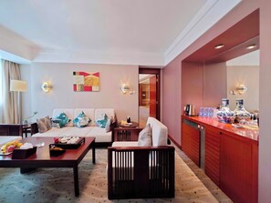 A hotel room with a sofa, a dining table, a small bar area, and a decorative wall piece. - Xiamen Jingmin Central Hotel (Xiamen)