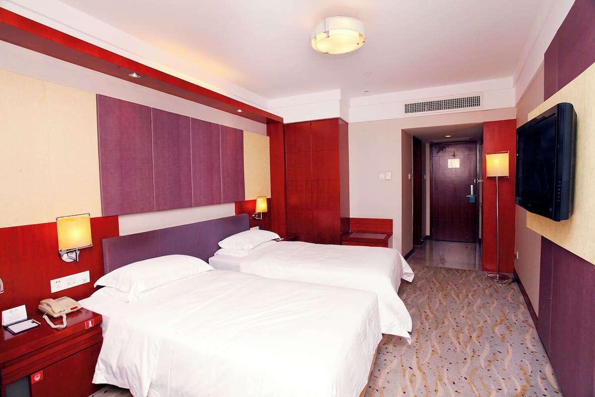 Une chambre d’hôtel avec deux lits, une télévision, un téléphone et une lampe.