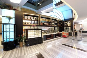 Un hall d’hôtel moderne avec un sol en marbre, une vitrine centrale et un plafond au design incurvé.