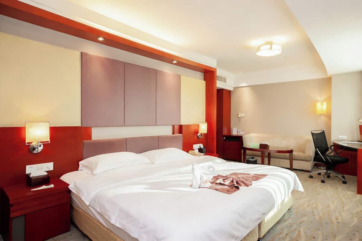 Une chambre d’hôtel avec un grand lit, des tables de chevet, un bureau et une chaise.