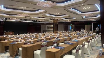 A conference room with rows of tables, chairs, and nameplates, equipped with microphones and laptops.