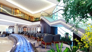 Eine moderne Hotelhalle mit einer gewundenen Wasserspüle, Sitzgelegenheiten, einer Treppe und Zimmerpflanzen.