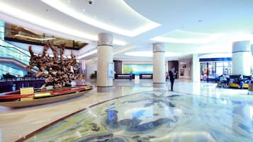 A spacious lobby with a large sculpture, a glass floor, and a modern ceiling design.