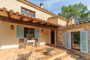 A rustic house with a tiled patio, wooden furniture, and a stone wall. - Lovely two bedroom villa with pool. Mireia (Pollensa / Pollença)