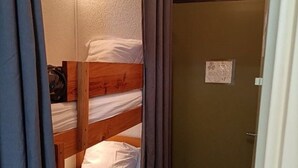 A bunk bed with white bedding and a wooden headboard.