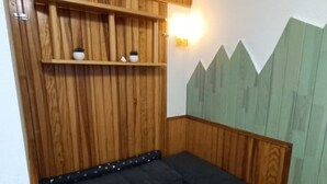 A wooden room with a bench, shelves, and a wall with a mountain design.