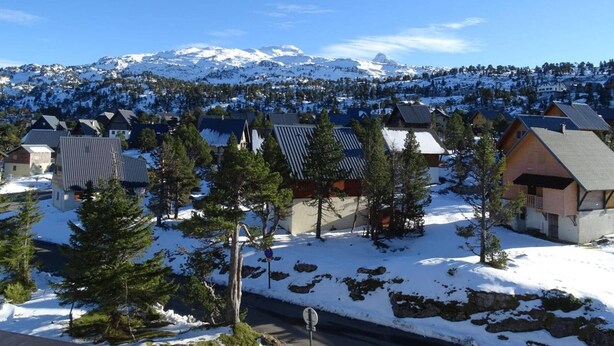 A snow-covered village with houses and a mountain range in the background.