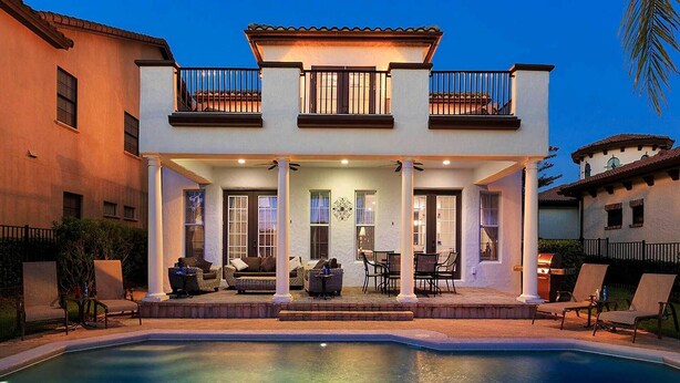 Une maison à deux étages dotée d’un patio couvert, d’une piscine et d’un balcon.