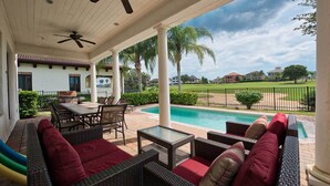 Un patio couvert avec une piscine, du mobilier d’extérieur et une vue sur un terrain de golf.