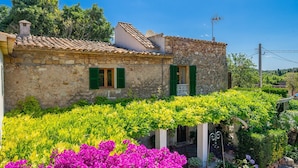 A stone house with green shutters, a tiled roof, and a garden with vibrant flowers. - Pollensa walking distance traditional villa Miquel (Pollensa / Pollença)