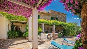 A covered outdoor area with stone walls, a stone fountain, and lounge chairs. - Pollensa walking distance traditional villa Miquel (Pollensa / Pollença)