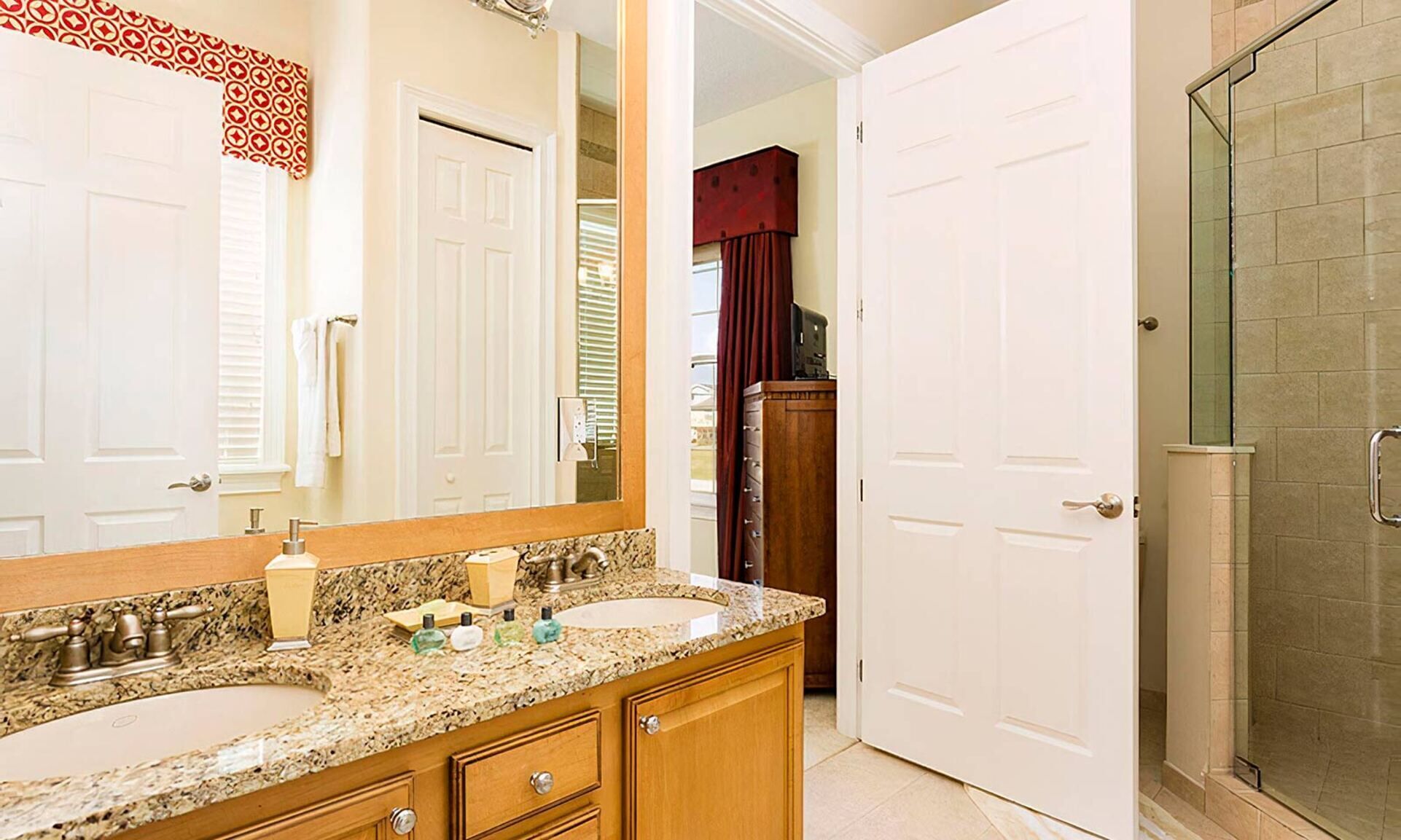 A bathroom with two sinks, a large mirror, and a shower area.