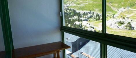 A room with a wooden bench and a large window offering a view of a mountainous landscape.