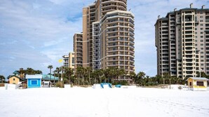 A beachfront hotel with multiple high-rise buildings, a sandy beach, and palm trees.