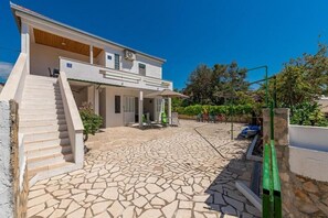A modern two-story house with a stone-tiled patio, a staircase leading to the entrance, and a covered outdoor seating area. - Holiday Home Vala in Vinišće (Vinišće)