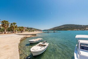 A marina with boats docked, clear water, and a hilly landscape in the background.