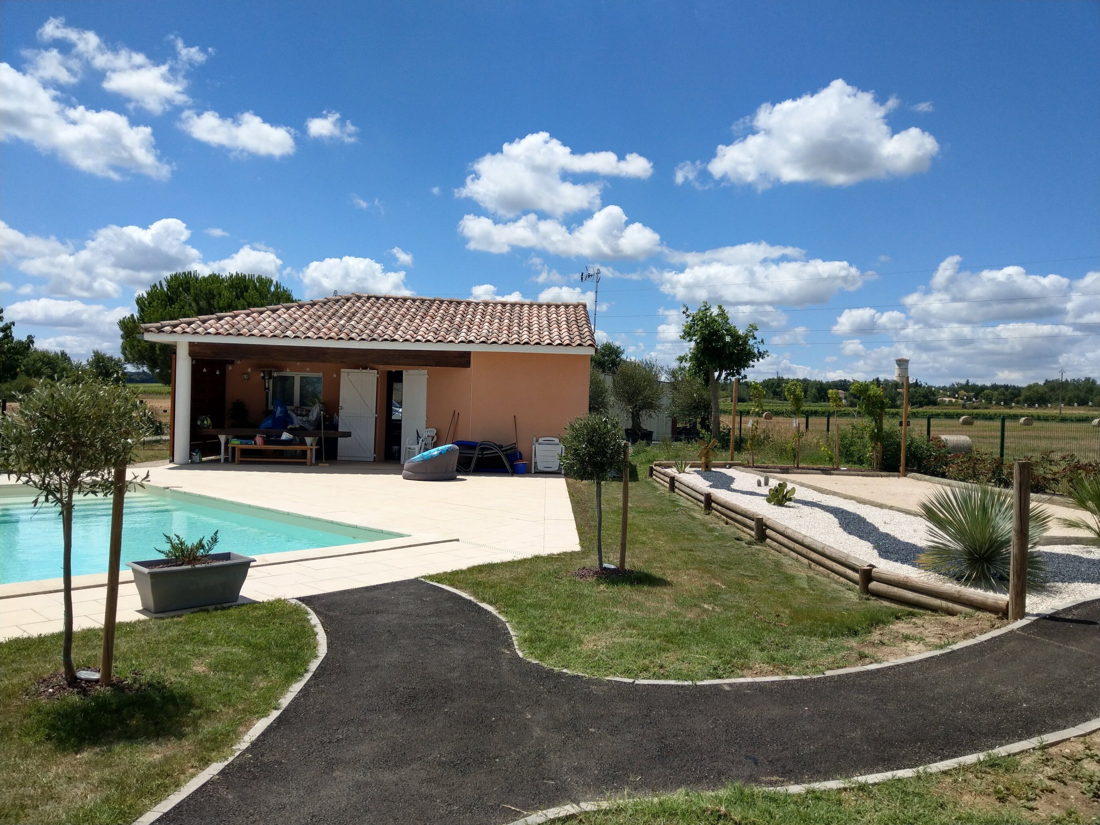 Una casa con techo de tejas, piscina y patio empavedado.