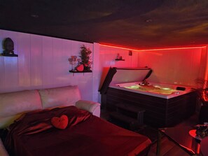 Una habitación con cama, sillón de masajes y bañera de hidromasaje.