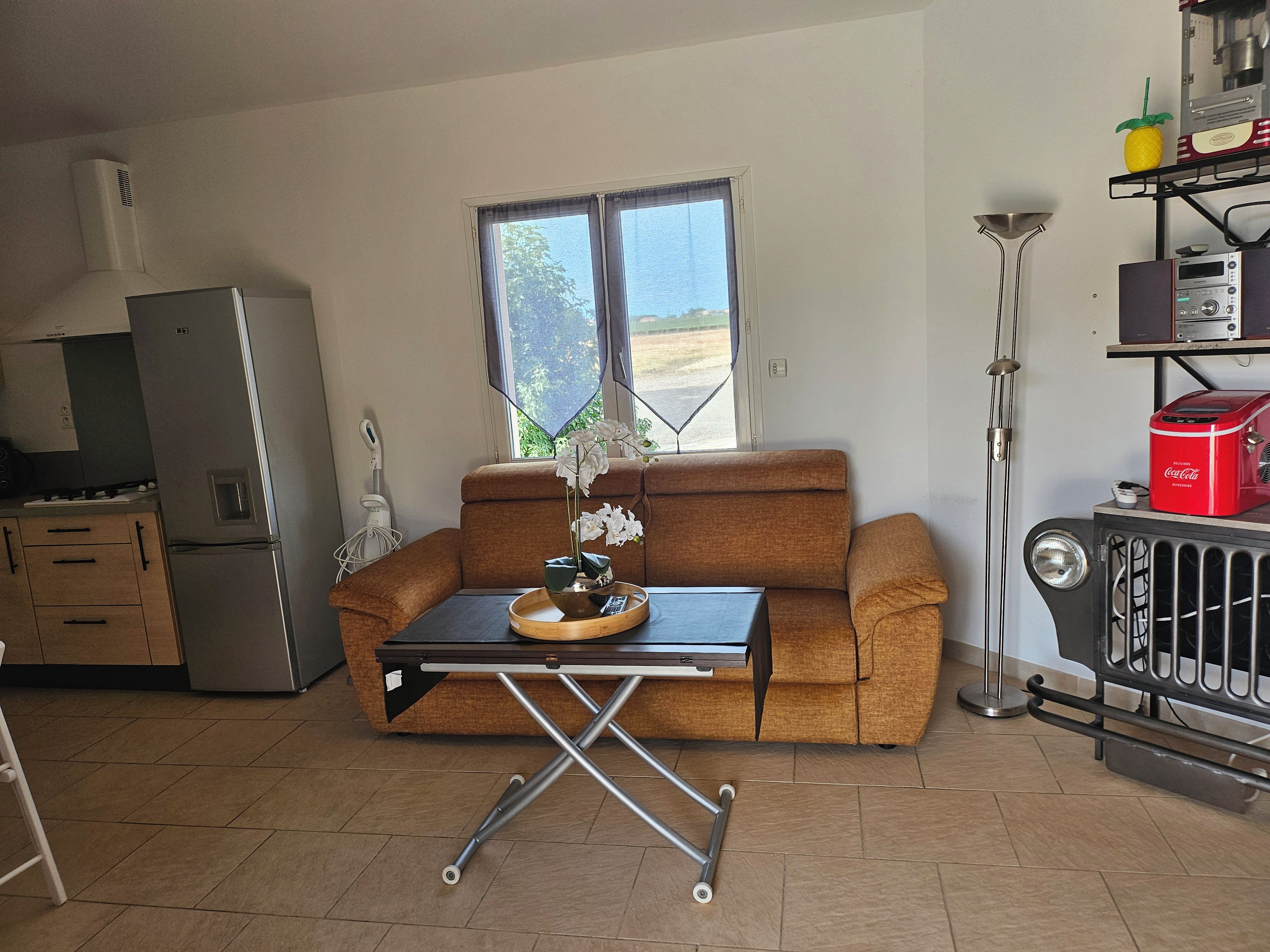 A compact living space with a kitchenette, a sofa, a small dining table, and a radiator.