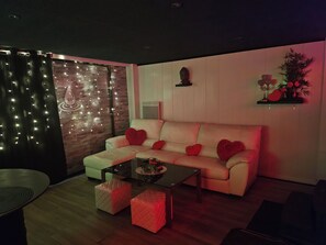 Una sala de estar moderna con un sofá, otomanas, una mesa de centro e iluminación decorativa.