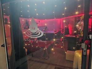A room with a glass partition, a bed, a desk, and a chair. There are string lights and a water feature. - The Font Blanque Bubbles (Campsas)