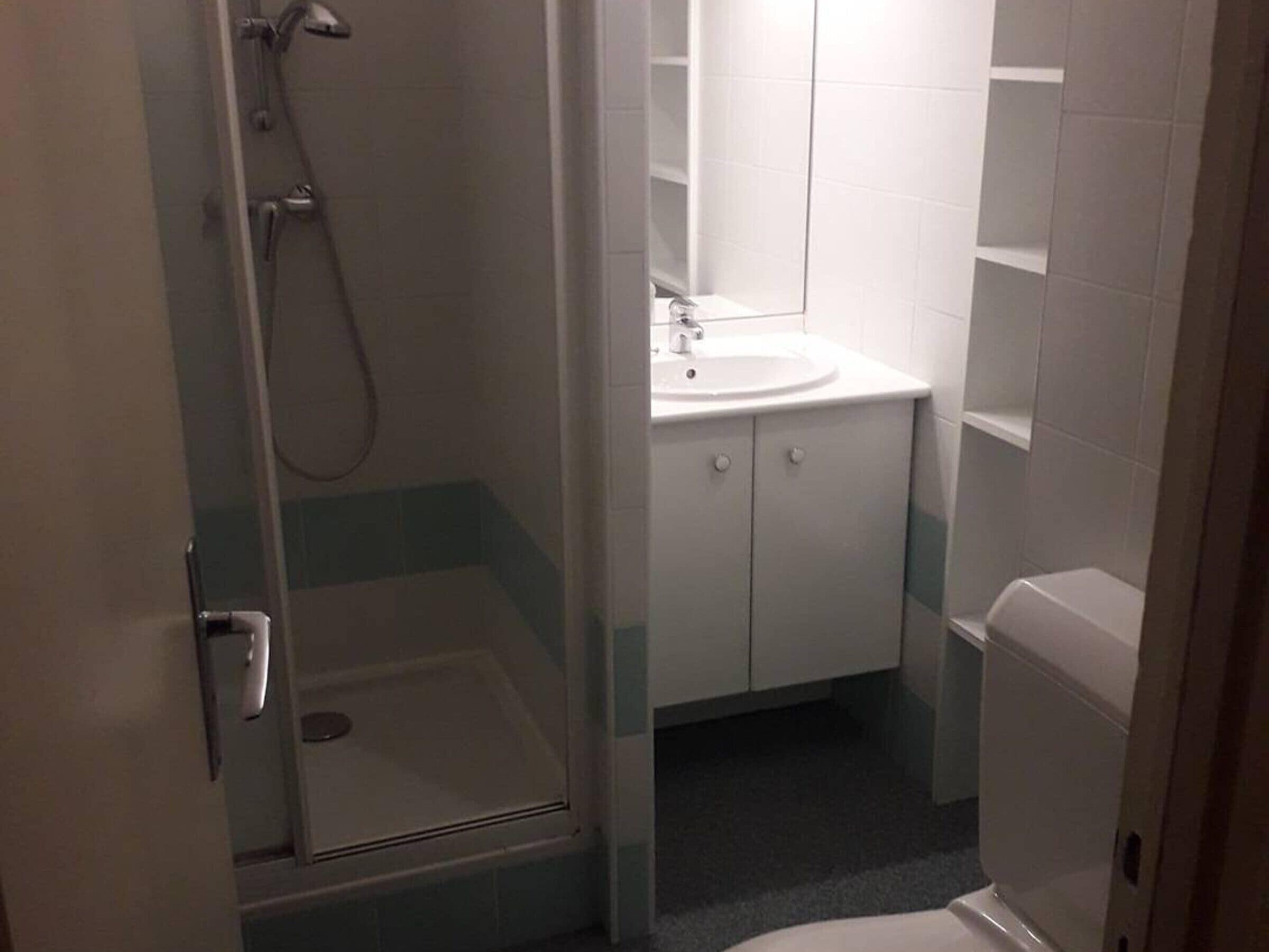 Une salle de bain avec une douche à parois de verre, un lavabo avec un miroir et des toilettes.