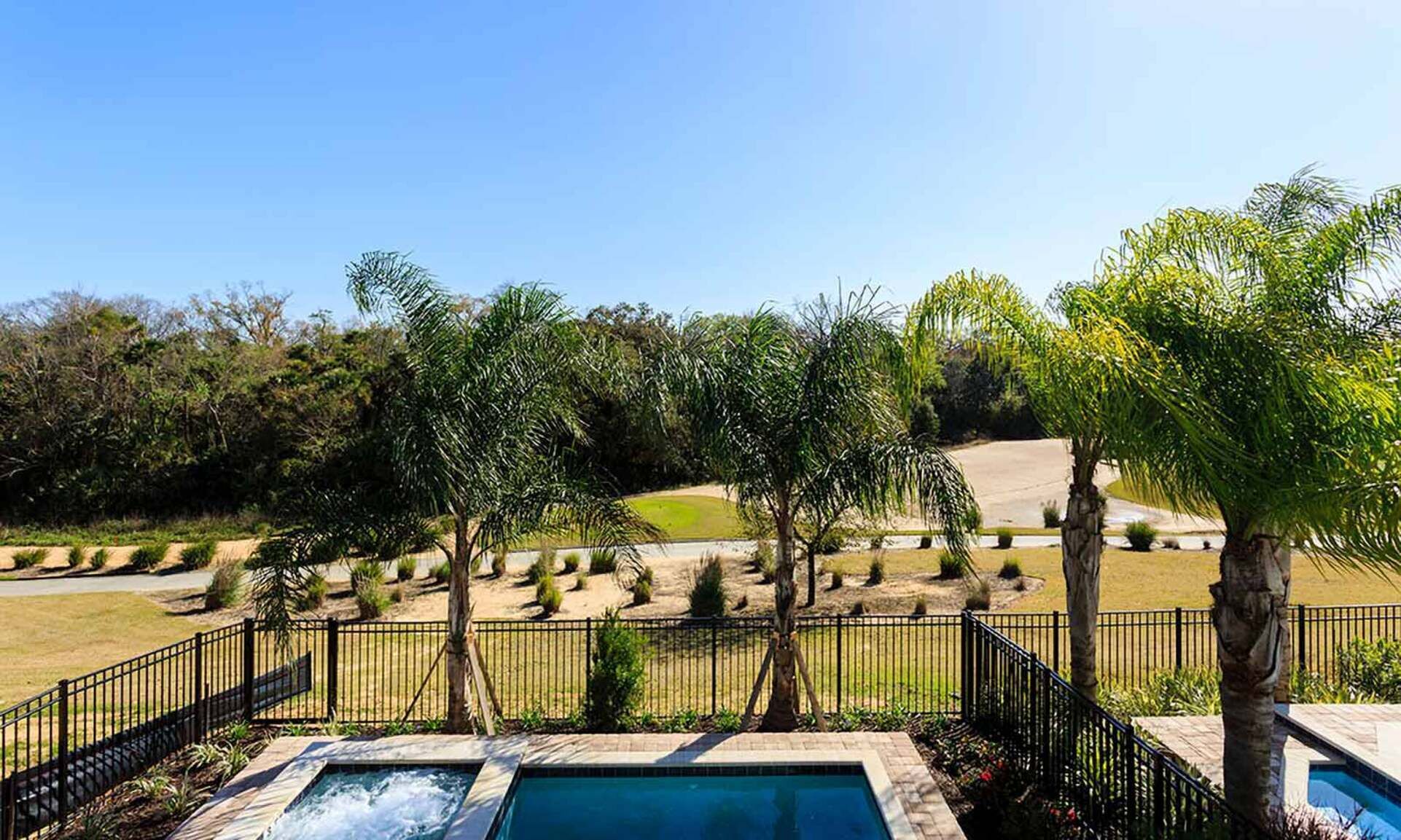 A pool area with a view of a landscaped garden and a hilly landscape in the background.